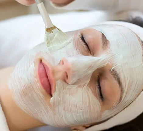 Cosmetician applying facial skincare mask to customer